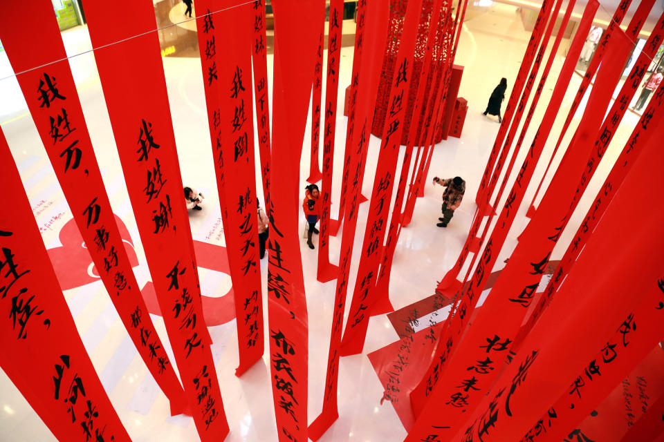 Long red ribbons with Chinese characters hang from the ceiling of an indoor mall
