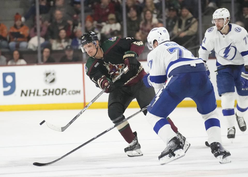 Arizona Coyotes center Nick Bjugstad (17) dumps the puck in against Tampa Bay Lightning defenseman Victor Hedman (77) during the second period at Mullett Arena in Tempe on Feb. 15, 2023.