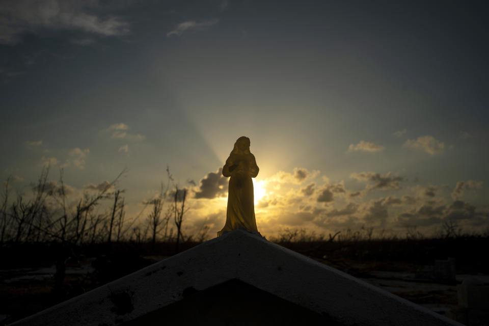 The sun sets behind a statuette of the Virgin Mary atop a grave broken by the force of Hurricane Dorian, in the cemetery of Mclean's Town, Grand Bahama, Bahamas, Wednesday Sept. 11, 2019. Bahamians are tackling a massive clean-up a week after Hurricane Dorian devastated the archipelago’s northern islands. Residents sift through debris as they try to save prized possessions and prepare to rebuild from one of the strongest Atlantic hurricanes in history. (AP Photo/Ramon Espinosa)