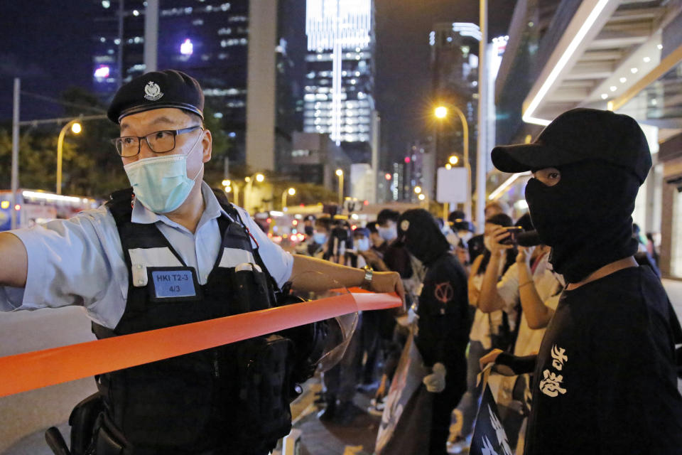 Police officers put up a cordon line in front of the protesters during a protest in Hong Kong. A report from an official Hong Kong police watchdog says officers used force only in response to threats to their safety. (AP Photo/Kin Cheung)