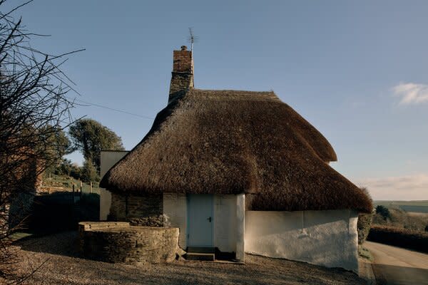 A bright blue front entry door pops against the home's historic thatched roof.