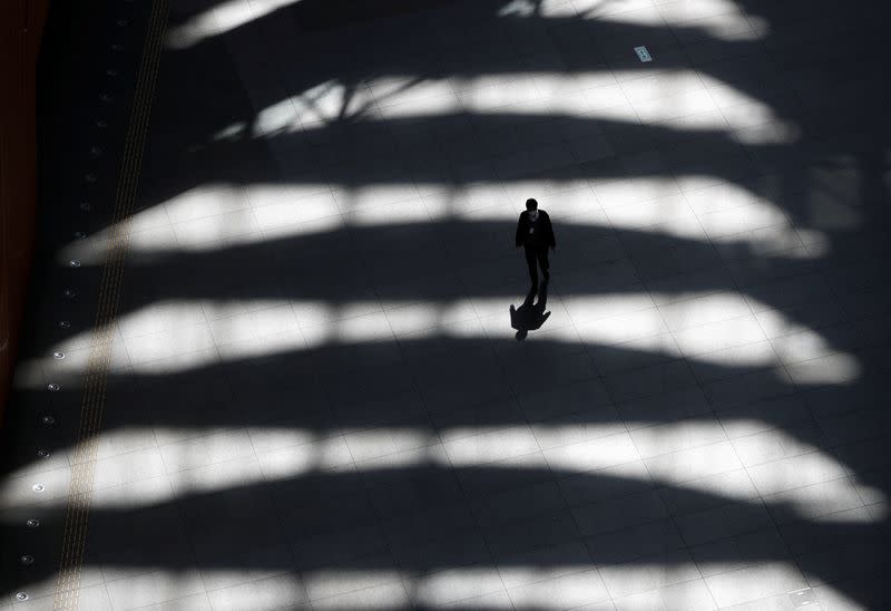 A man wearing a protective face mask, following an outbreak of the coronavirus disease, walks past inside an almost empty convention complex in Tokyo, Japan