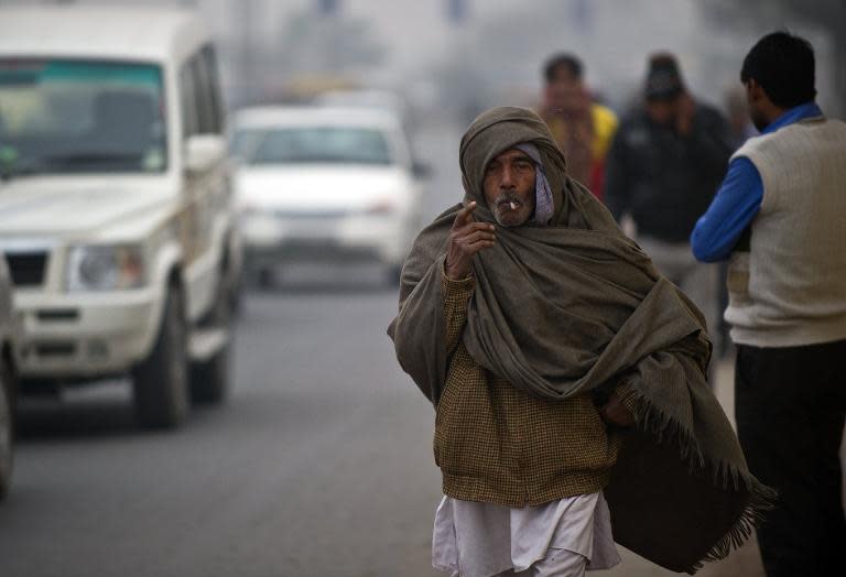 An Indian pedestrian, wrapped in a blanket, smokes a biddi (leaf cigarette) in New Delhi on January 31, 2014