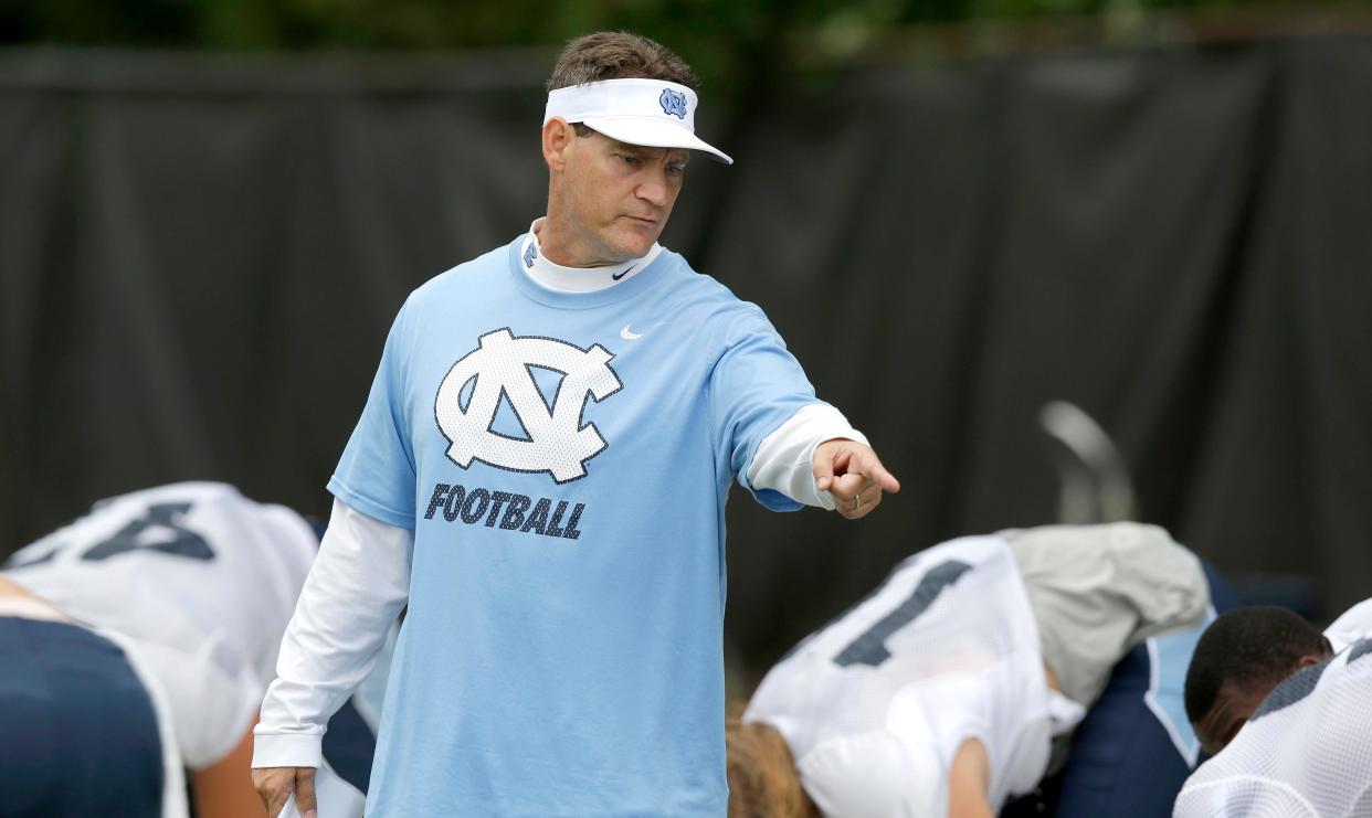 In this photo from August 2015, North Carolina defensive coordinator Gene Chizik makes a point to Tar Heels players during a football practice.