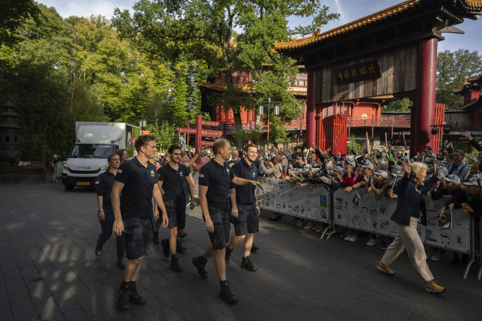 Zookeepers escort the van carrying giant panda Fan Xing, rear, who's heading home to a country she has never visited, as it leaves the Ouwehands Zoo in Rhenen, Netherlands, Wednesday, Sept. 27, 2023. The 3-year-old was carefully ushered into a crate for the first leg of her journey to China, where she will join a captive breeding program that is helping preserve the vulnerable species. (AP Photo/Peter Dejong)