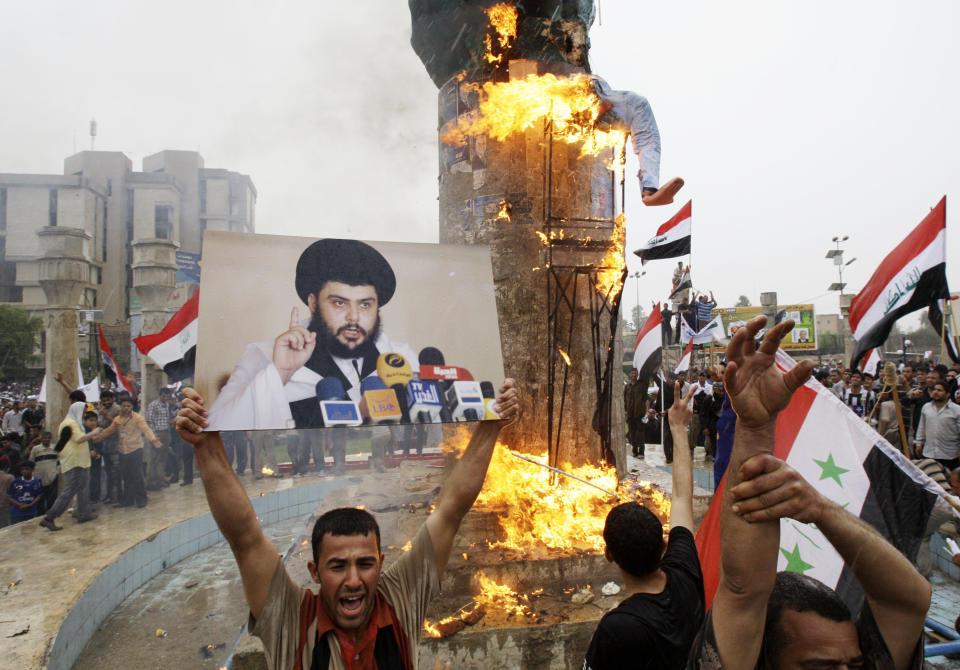 FILE - Supporters of anti-U.S. Shiite cleric Muqtada al-Sadr, seen in a poster at left, burn an effigy representing former U.S. President George W. Bush in central Baghdad, Iraq, Thursday, April 9, 2009, for a rally marking the sixth anniversary of the fall of the Iraqi capital to American troops. Al-Sadr is a populist cleric, who emerged as a symbol of resistance against the U.S. occupation of Iraq after the 2003 invasion. (AP Photo/Karim Kadim, File)