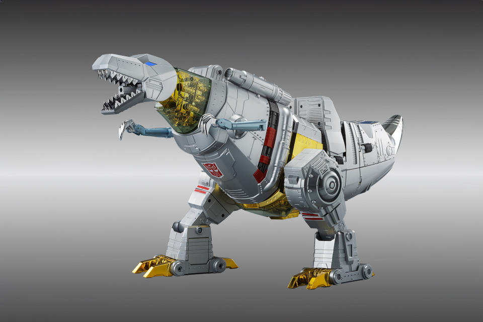 The self-transforming Grimlock toy from Robosen. It stands (in T-Rex form) roaring feriociously to the left in front of a gray gradient background.