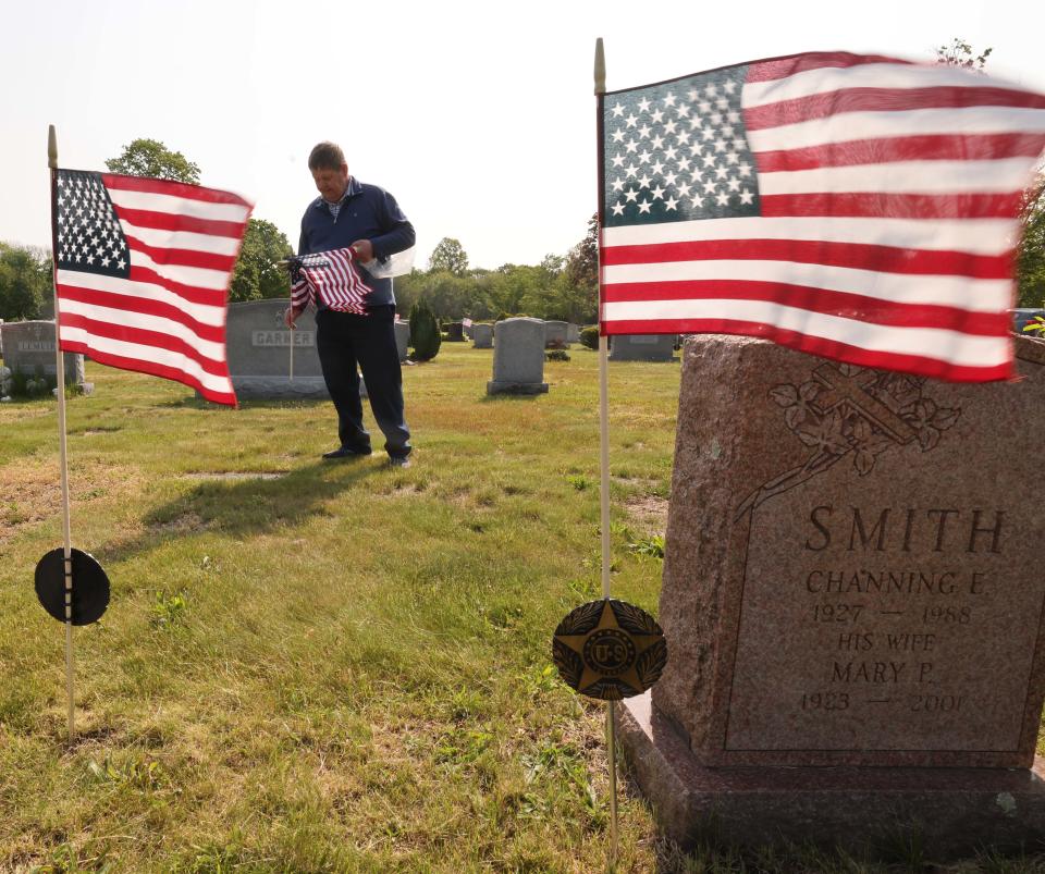 State Rep. Gerard Cassidy places American flags at the gravestones of veterans in Melrose Cemetery in Brockton in preparation for Memorial Day on Monday, May 22, 2023.