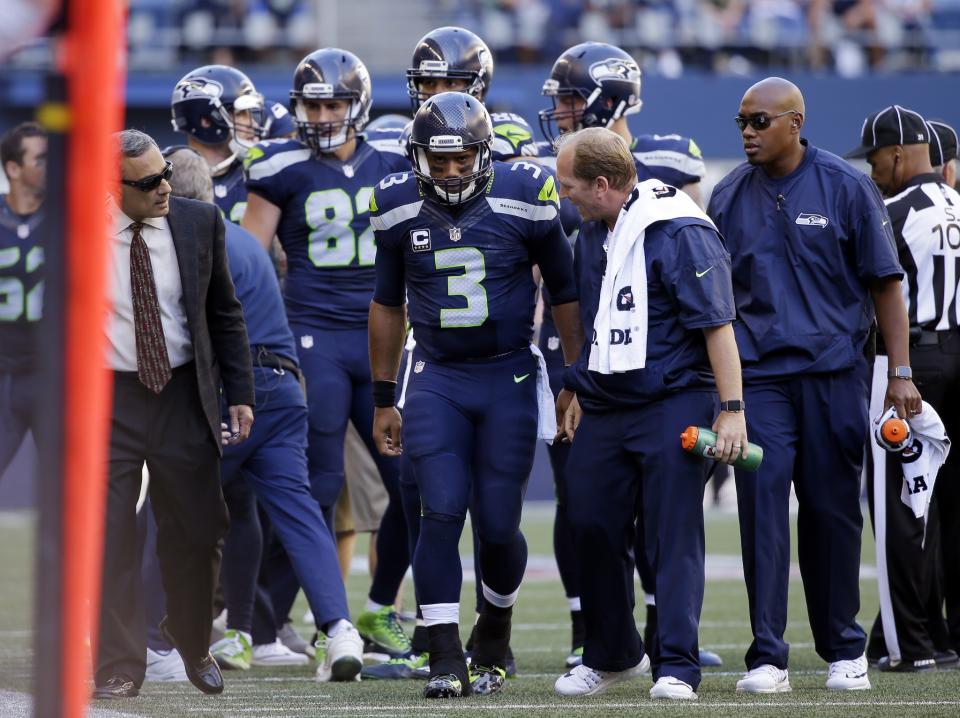 Seattle Seahawks QB Russell Wilson, middle, is going through a lot to play Sunday (AP).