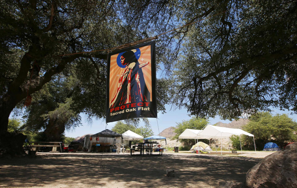 FILE - A banner hangs in an encampment belonging to protesters in the Oak Flat area of Superior, Ariz., on June 15, 2015. A federal agency says an environmental review for a proposed copper mine in Arizona falls short on details about water and the potential impacts of climate change. (AP Photo/Ross D. Franklin, File)