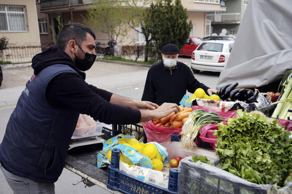 A street vendor wearing a mask to help protect against the spread of coronavirus, serves a client hours before a two-day weekend nationwide lockdown, in Ankara, Turkey, Friday, April 16, 2021. Turkey's daily tally of COVID-19 deaths reached a record high of 341 on Monday, April 19, 2021, Health Ministry data showed. The deaths take the official toll to 34,267, in the country which now ranks among the world's worst-hit. (AP Photo/Burhan Ozbilici)