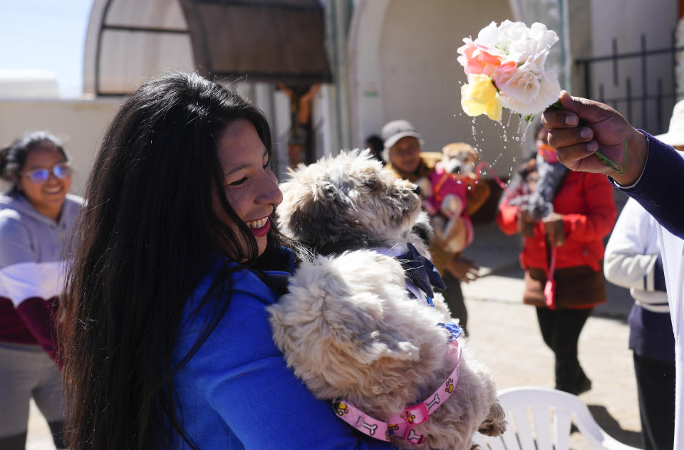 El párroco católico Justino Limachi bendice a perros con agua bendita durante la misa en la iglesia del Cuerpo de Cristo para celebrar la fiesta de San Roque, considerado el santo patrón de los perros, en El Alto, Bolivia, el miércoles 16 de agosto de 2023. (AP Foto/Juan Karita)