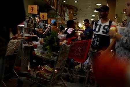 A man waits in line to pay for food at the cashier of a supermarket in Caracas, Venezuela March 10, 2017. REUTERS/Carlos Garcia Rawlins