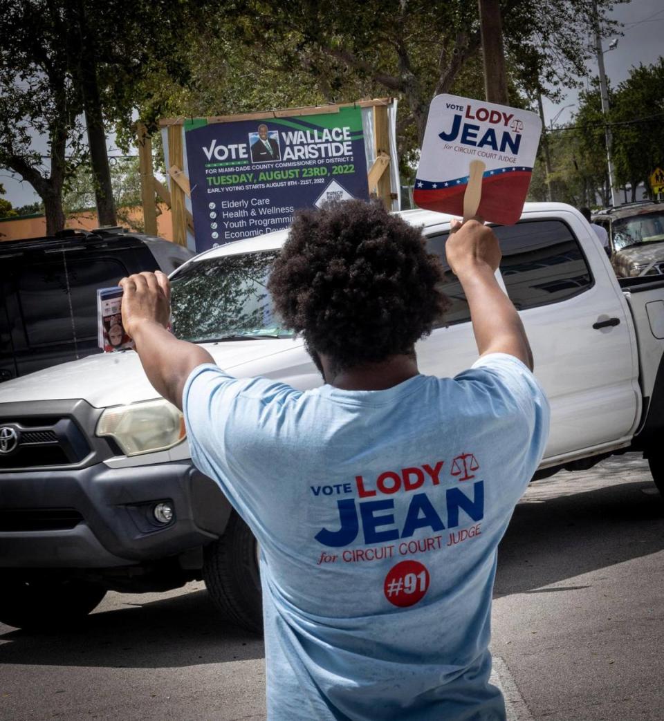 A poll worker for judicial candidate Lody Jean tries to get a voter’s attention in front of the North Miami Library on Aug. 9, 2022, as early voting continues in Miami-Dade County. Haitian-American officials in Miami-Dade County held a press conference to denounce attacks on Haitian-American judges in the 2022 elections.
