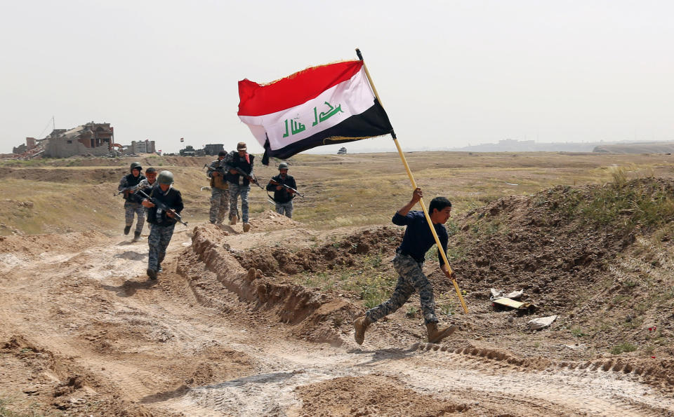 This Monday, March 30, 2015 file photo shows a member of the Iraqi security forces running to plant the national flag as they surround Tikrit during clashes to regain the city from Islamic State militants, 80 miles  north of Baghdad, Iraq. (AP Photo/Khalid Mohammed, File)