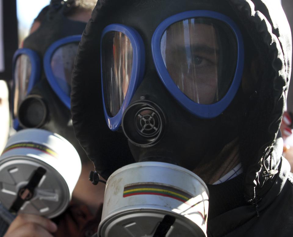 Demonstrators wear gasmasks as they protest against the dismantling of Syrian chemical weapons in Albania in front of the Prime Minister's office in Tirana