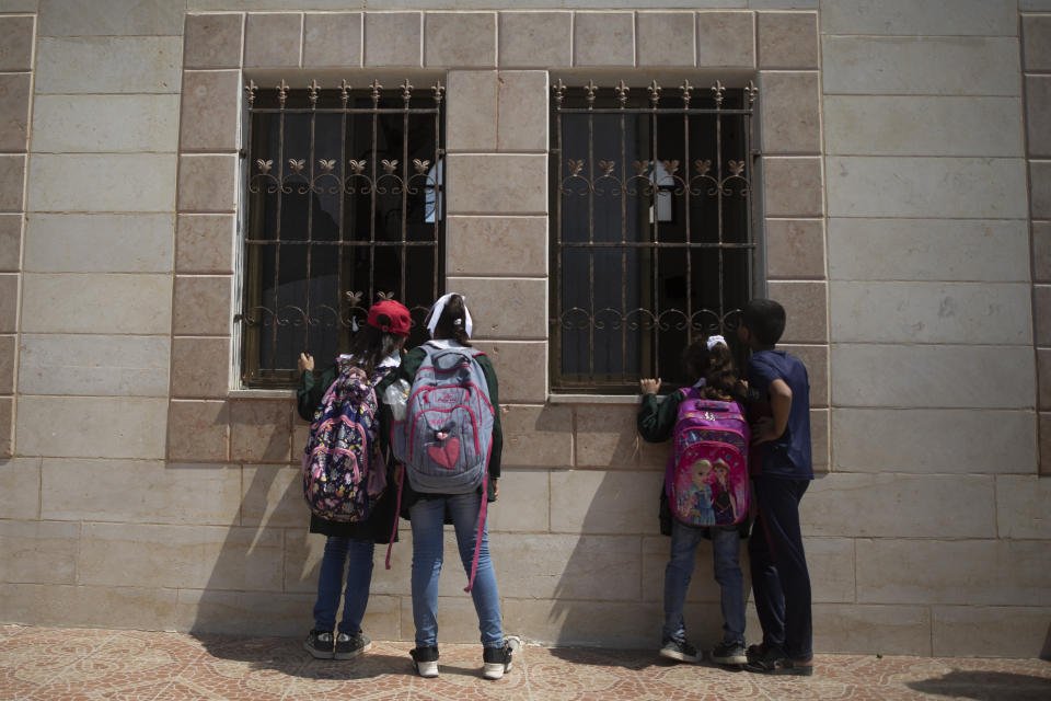 School children look from the windows of a mosque at the body of Palestinian Omar al-Nile, 12, who was shot on Saturday during a violent demonstration on the eastern border between Gaza and Israel, during his funeral in Gaza City, Saturday, Aug. 28, 2021. (AP Photo/Khalil Hamra)