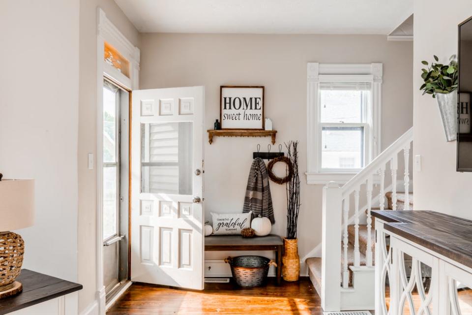 a rustic entry way with a white door and wood floors and white railing 