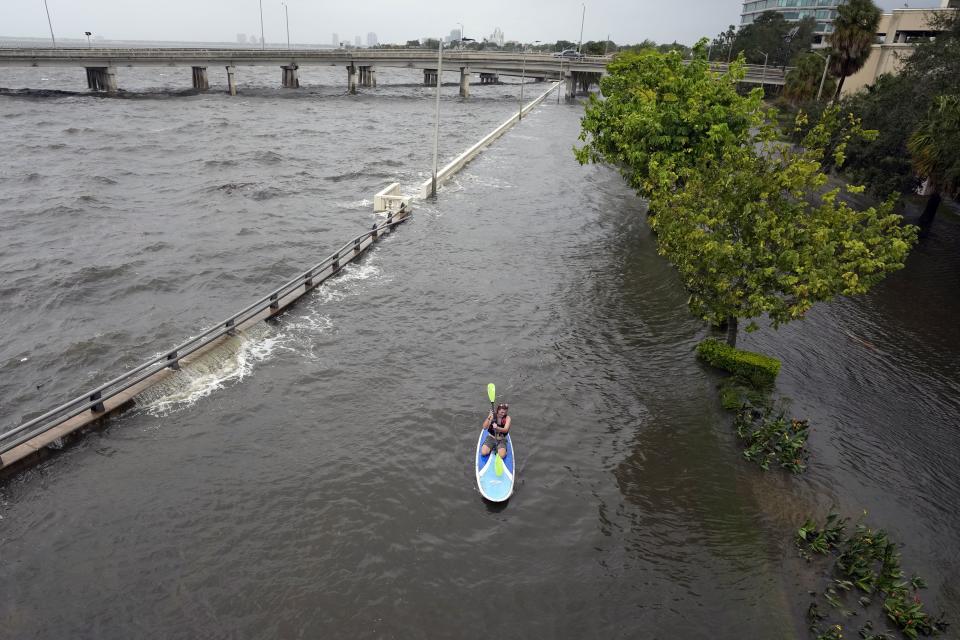Flood waters pushed by Hurricane Idalia pour over the sea wall along Old Tampa Bay as paddle boarder Zeke Pierce, of Tampa rides Wednesday, Aug. 30, 2023, in Tampa, Fla. Idalia made landfall earlier this morning along the Big Bend of the state. (AP Photo/Chris O'Meara)