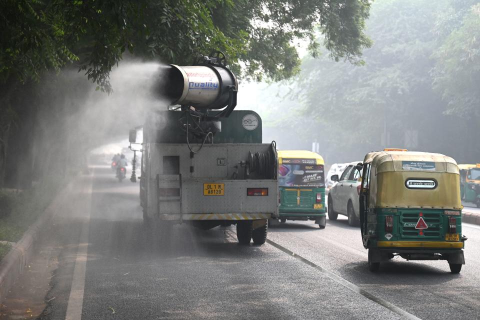 Commuters drive past a truck equipped with an anti-smog gun, spraying water to curb air pollution amid heavy smog conditions in New Delhi, India, November 4, 2022. / Credit: MONEY SHARMA/AFP/Getty