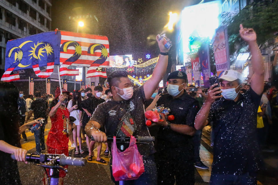 A policeman tries to disperse the crowd gathered for the New Year countdown along Jalan Bukit Bintang in Kuala Lumpur December 31, 2021. &#x002014; Pictures by Choo Choy May