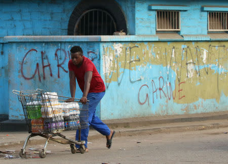 A man pushes a trolley full of groceries as he passes a graffiti referring to former Vice President Emmerson Mnangagwa, who was sacked, in Harare, Zimbabwe November 15, 2017. REUTERS/Philimon Bulawayo