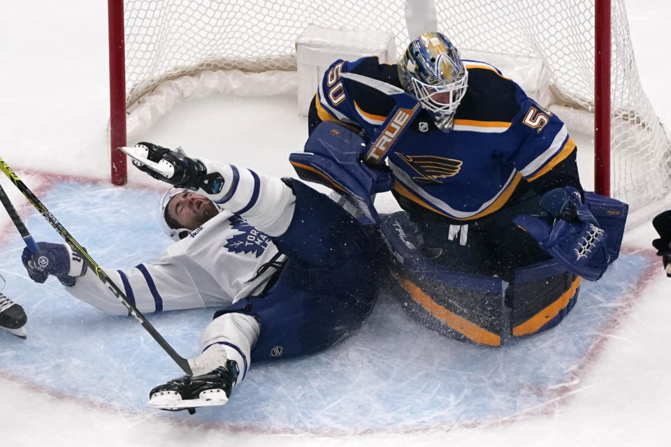 Toronto Maple Leafs' TJ Brodie, left, collides with St. Louis Blues goaltender Jordan Binnington during overtime of an NHL hockey game Tuesday, Dec. 27, 2022, in St. Louis. Brodie was awarded a penalty shot on the play but failed to score. (AP Photo/Jeff Roberson)