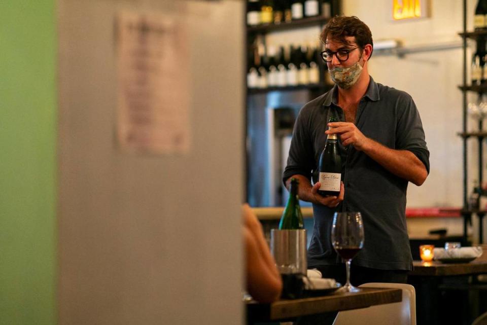 David Foulquier, 30, serves champagne to customers during the opening day of a new pop-up, Da Lida, which operates at his French-Persian restaurant Fooq’s in downtown Miami, Florida, on Tuesday, October 27, 2020.