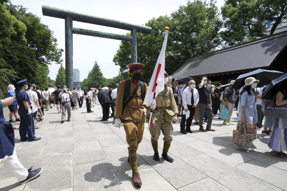 Visitors in old Japanese Imperial army uniforms enter Yasukuni Shrine, which honors Japan's war dead Monday, Aug. 15, 2022, in Tokyo. Japan marked the 77th anniversary of its World War II defeat Monday. (AP Photo/Eugene Hoshiko)