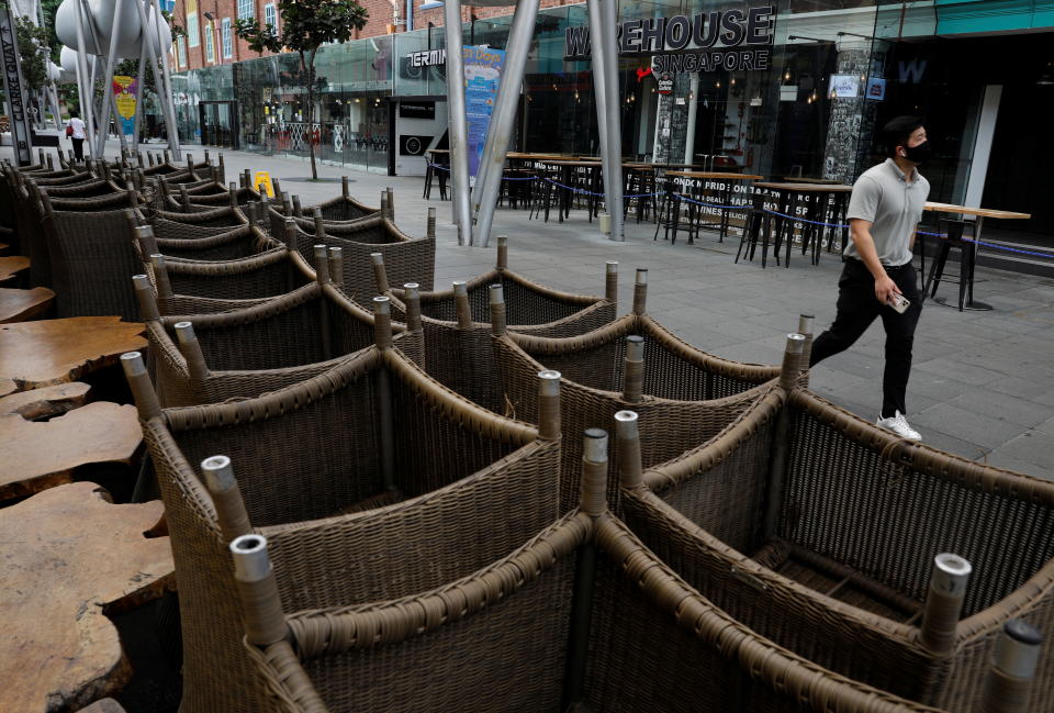 A man walks past chairs stacked up outside restaurants as dining-in is restricted to curb the coronavirus disease (COVID-19) outbreak in Singapore May 17, 2021.   REUTERS/Edgar Su