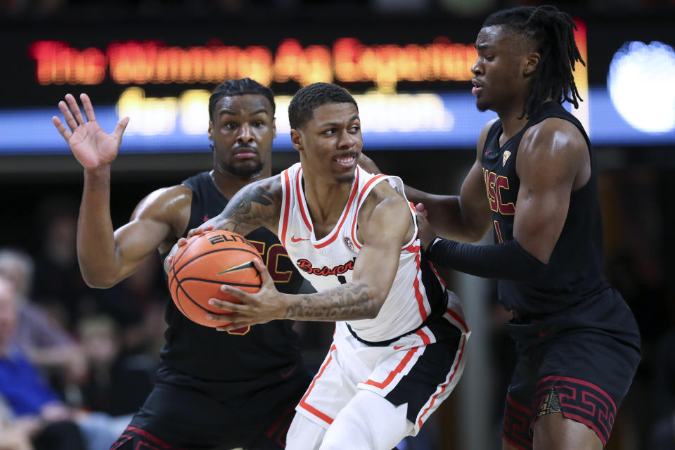 Oregon State guard Christian Wright, center, looks to pass the ball as Southern California's Bronny James, left, and Isaiah Collier defend during the second half of an NCAA college basketball game Saturday, Dec. 30, 2023, in Corvallis, Ore. Oregon State won 86-70. (AP Photo/Amanda Loman)