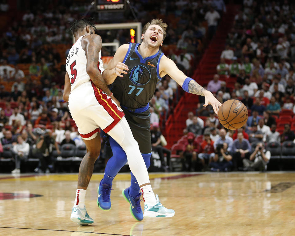 Dallas Mavericks forward Luka Doncic (77) is fouled by Miami Heat forward Derrick Jones Jr. (5) as he drives to the basket during the first half of an NBA basketball game, Thursday, March 28, 2019, in Miami. (AP Photo/Joel Auerbach)