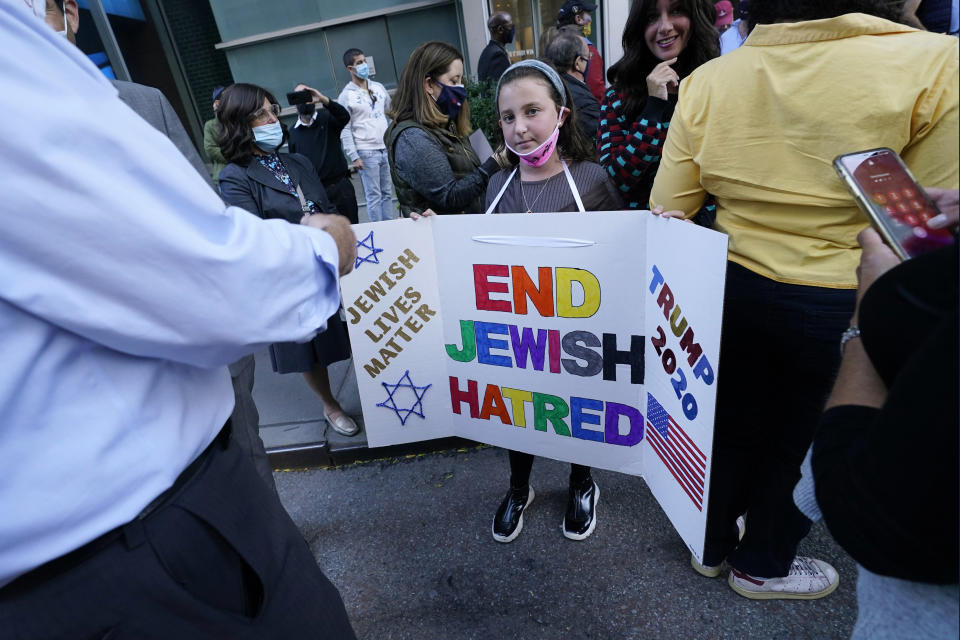 FILE - In this Thursday, Oct. 15, 2020 file photo, a young girl holds a poster she made as she prepares to pose for a cell phone photograph for a relative as she and others joined protesters outside the offices of New York Gov. Andrew Cuomo in New York. Three Rockland County Jewish congregations are suing New York state and Cuomo, saying he engaged in a "streak of anti-Semitic discrimination" with a recent crackdown on religious gatherings to reduce the state's coronavirus infection rate. (AP Photo/Kathy Willens)