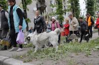 Women walk to clean streets in Volnovakha, in territory under the government of the Donetsk People's Republic, eastern Ukraine, Monday, May 23, 2022. (AP Photo)