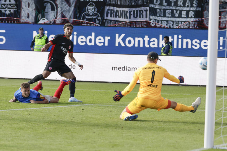 Frankfurt's Omar Marmoush, centre, scores his side's third goal past Kiel's Carl Johansson, left, and goalkeeper Timon Weiner during the Bundesliga soccer match between Holstein Kiel and Eintracht Frankfurt, at the Holstein Stadium in Kiel, Germany, Sunday, Sept. 29, 2024. (Frank Molter/dpa via AP)