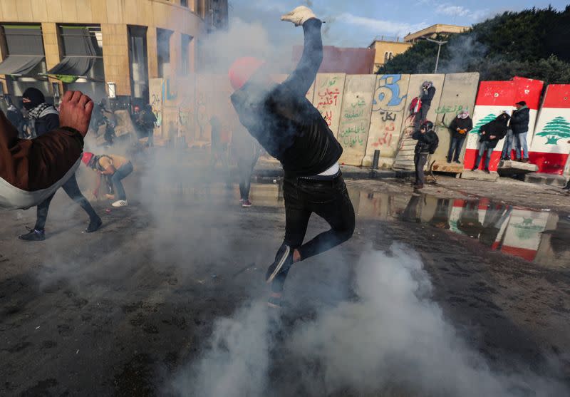 A protestor throws back a tear gas canister during a protest seeking to prevent MPs and government officials from reaching the parliament for a vote of confidence