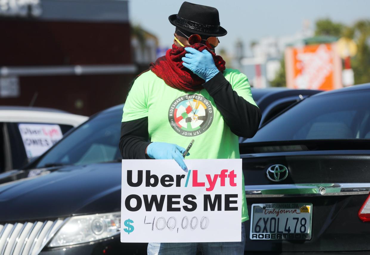 uber lyft protest drivers LOS ANGELES, CALIFORNIA - APRIL 16: A protestor displays a sign as Uber and Lyft drivers with Rideshare Drivers United and the  Transport Workers Union of America prepare to conduct a ‘caravan protest’ outside the California Labor Commissioner’s office amidst the coronavirus pandemic on April 16, 2020 in Los Angeles, California. The drivers called for California to enforce the AB 5 law so that they may qualify for unemployment insurance as the spread of COVID-19 continues. Drivers also called for receiving back wages they say they are owed. (Photo by Mario Tama/Getty Images)