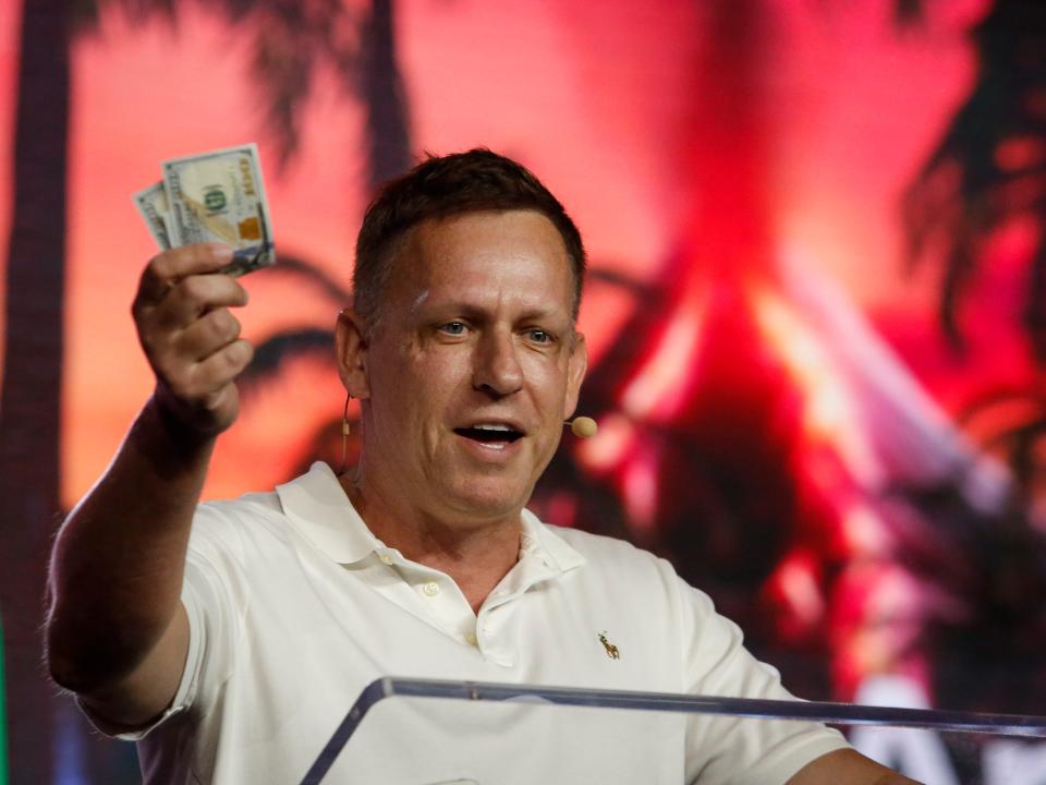 Peter Thiel, co-founder of PayPal, Palantir Technologies, and Founders Fund, holds hundred dollar bills as he speaks during the Bitcoin 2022 Conference at Miami Beach Convention Center on April 7, 2022 in Miami, Florida. 