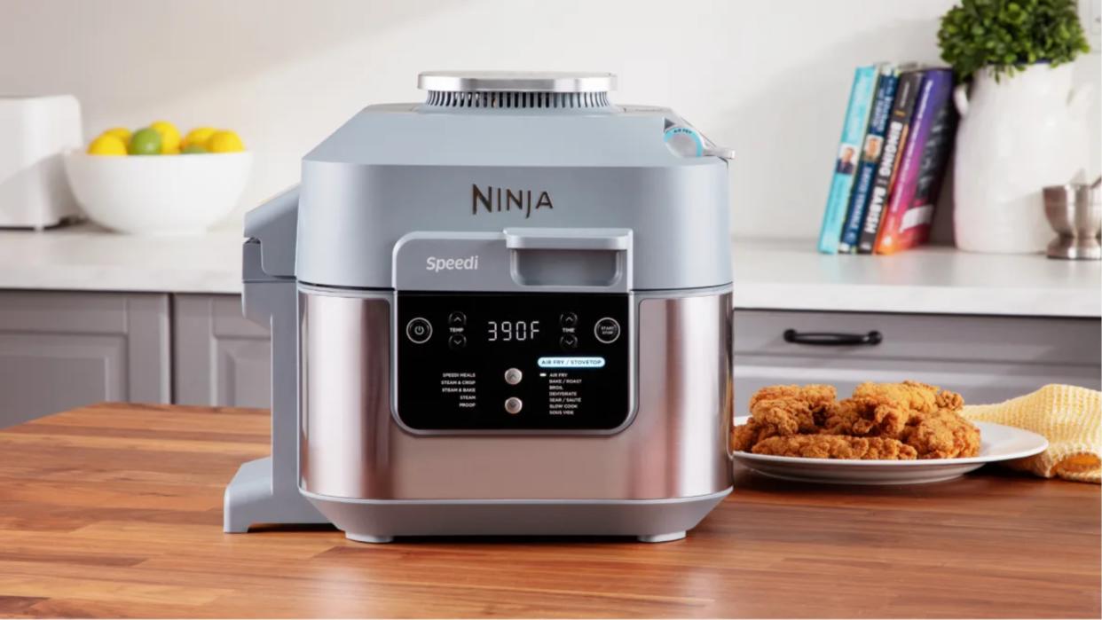  Ninja Speedi multicooker and air fryer on wooden countertop with cookbooks in background. 