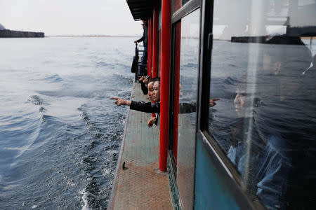 Tourists look from a boat taking them from the Chinese side of the Yalu River for sightseeing close to the shores of North Korea, near Dandong, China's Liaoning province, April 1, 2017. REUTERS/Damir Sagolj