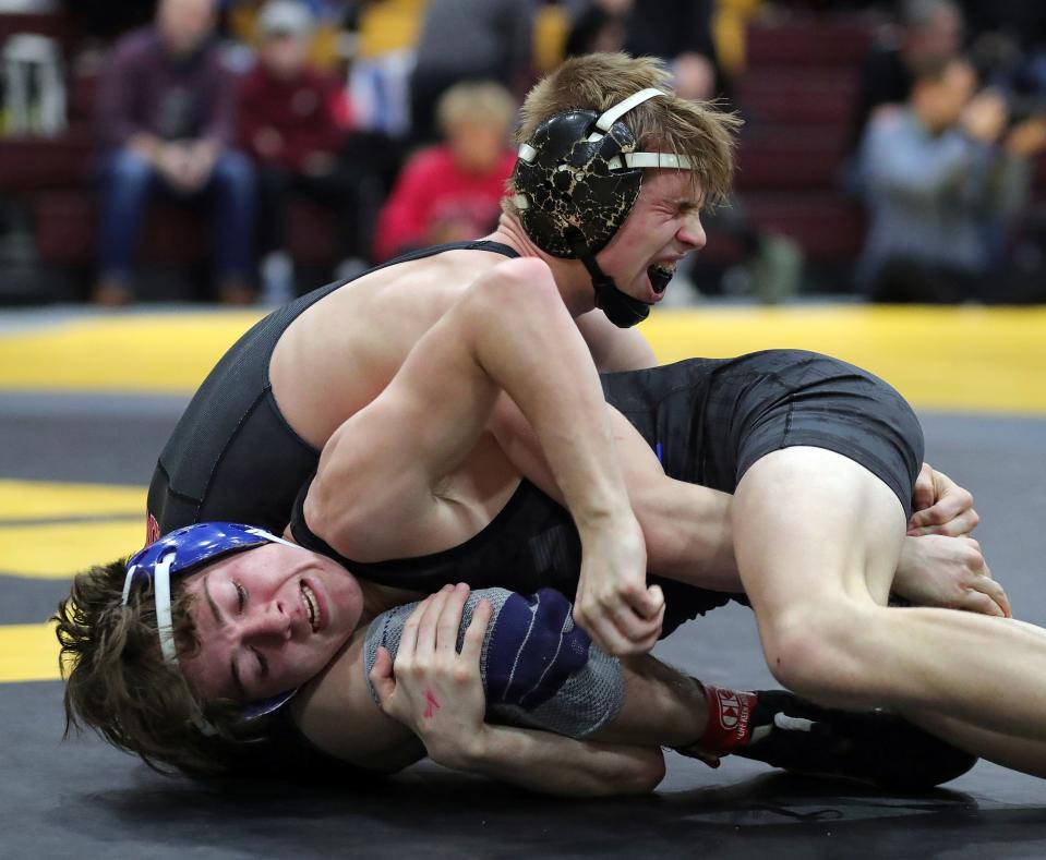 Brecksville's Rylan Seacrist, top, winces in pain as he pushes through his 113-pound match against Liberty's Hunter Taylor after an injury in the semifinal round of the Ironman wrestling tournament Saturday at Walsh Jesuit High School.