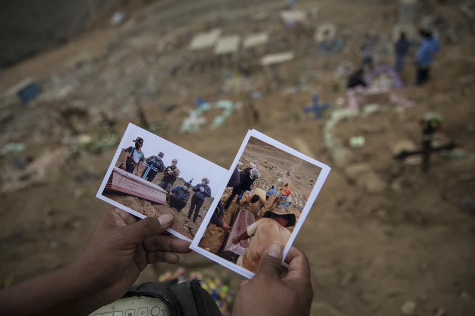 A street photographer sells pictures to the relatives of Adrian Tarazona Manrique, 72, who died of COVID-19 complications, during his burial at the Nueva Esperanza cemetery on the outskirts of Lima, Peru, Thursday, May 28, 2020. (AP Photo/Rodrigo Abd)