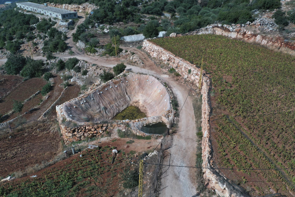 An innovative artificial pond is seen between agricultural fields at Harf Beit Hasna village, in Dinnieh province, north Lebanon, Wednesday, Sept. 7, 2022. Farmers in a small mountainous town in Lebanon's northern Dinnieh province once could rely on rain to irrigate their crops and sustain a living. But climate change and the country's crippling economic crisis has left their soil dry and their produce left to rot. They rely on the little rain they can collect in their innovative artificial ponds to make enough money to feed themselves, as they live without government electricity, water, and services. (AP Photo/Hussein Malla)