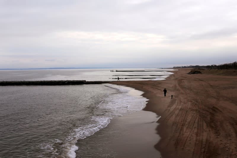 FILE PHOTO: A man walks his dog on a nearly empty South beach during the coronavirus outbreak in Staten Island