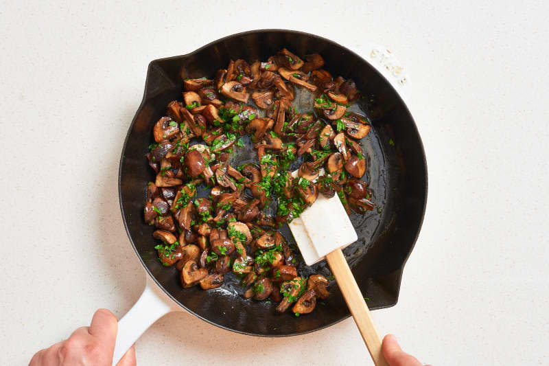 Pan with cooked mushrooms in melted butter with chopped fresh parsley