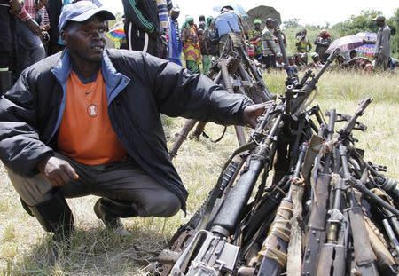 A militant from the Democratic Forces for the Liberation of Rwanda (FDLR) squats near a pile of weapons after their surrender in Kateku, a small town in eastern region of the Democratic Republic of Congo (DRC), May 30, 2014. REUTERS/Kenny Katombe