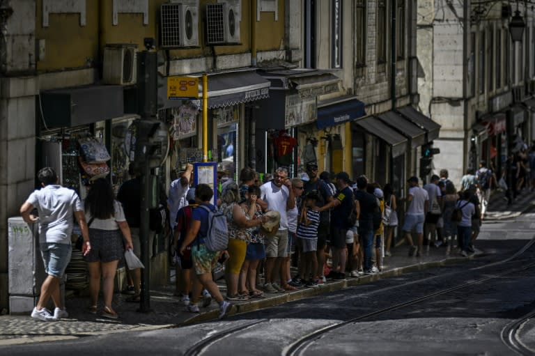 Unos turistas esperan el autobús en una parada del centro de Lisboa el 16 de agosto de 2023 (Patricia de Melo Moreira)