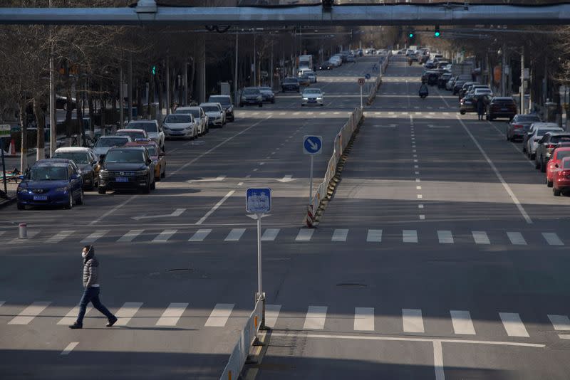 Man wearing a face mask crosses a road, as the country is hit by an outbreak of the novel coronavirus, in Beijing