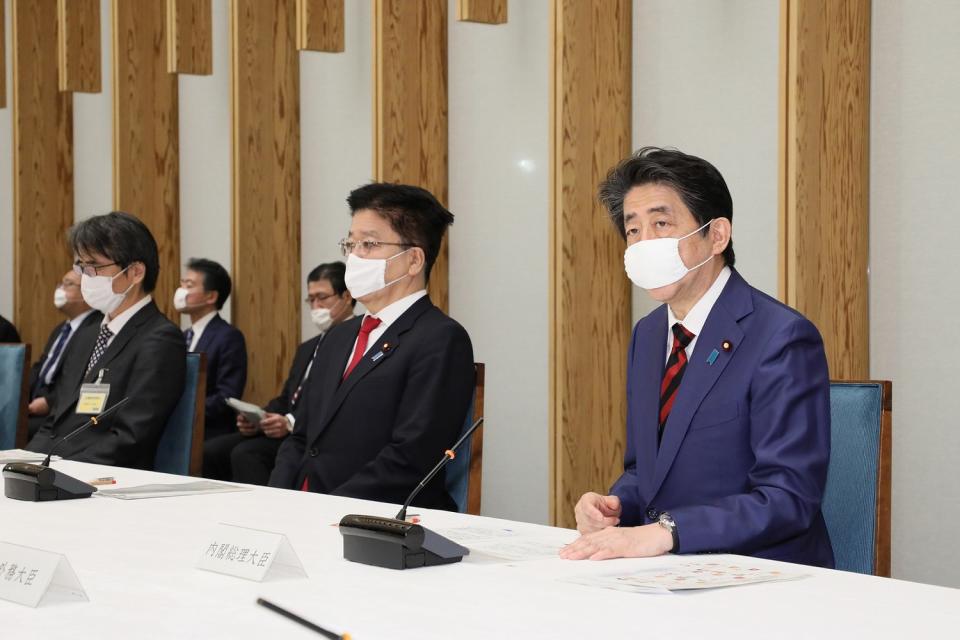 日本首相安倍晉三（右）22日出席記者會，戴的口罩尺寸明顯不合，只能勉強棄住口鼻。   圖：翻攝自日本首相官邸