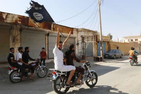 A resident of Tabqa city touring the streets on a motorcycle waves an Islamist flag in celebration after Islamic State militants took over Tabqa air base, in nearby Raqqa city August 24, 2014. REUTERS/Stringer